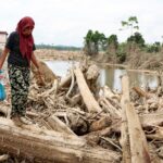 Indonesians climb over logs in walk to aid centre as flood deaths exceed 900